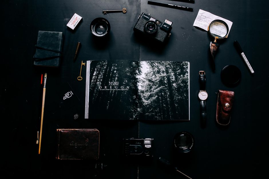 A creative flat lay of vintage cameras, lenses, and accessories on a dark background.